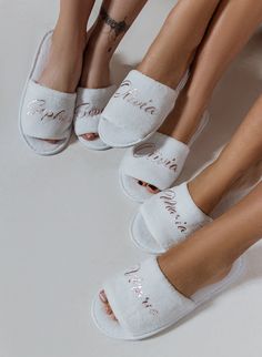 three women wearing white slippers with writing on the bottom and one has her legs crossed