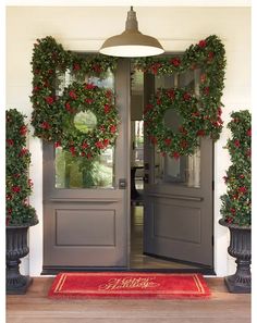 the front door is decorated with christmas wreaths and poinsettia plants for holiday decor