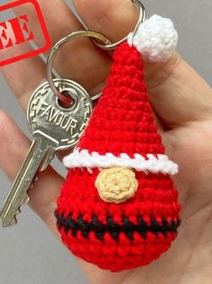 a hand holding a crocheted key chain with a santa hat on it's side