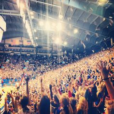 a large crowd at a basketball game is throwing confetti in the air