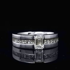 a white gold ring set with an emerald cut diamond and channeled diamonds on each band