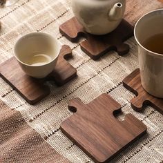 a cup of tea sits next to two pieces of wooden puzzles on a table