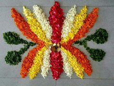 a colorful flower arrangement on the ground with a bell in it's center, surrounded by leaves and flowers