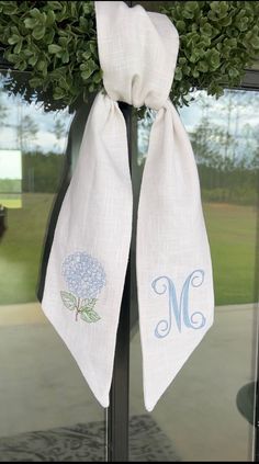 two monogrammed tea towels hang from a door handle with the letter m on it