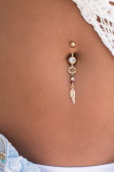 a woman's stomach with a gold belly ring and an earring on it