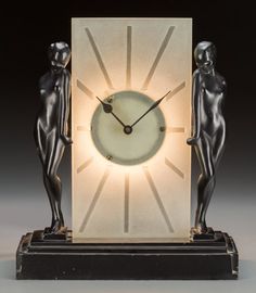 an art deco clock with two female figures on the front and back, lit up by a light bulb