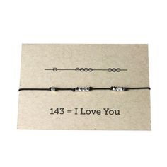 a black string bracelet that says,'i love you'with two small beads on it