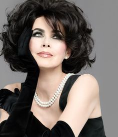 a woman with black hair and pearls on her neck