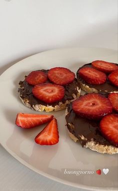 two desserts with chocolate frosting and strawberries on top are sitting on a white plate