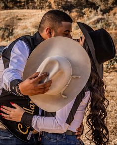 a man and woman hugging each other with cowboy hats on their heads