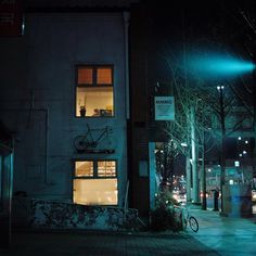 a bicycle parked in front of a building on a city street at night with the lights on