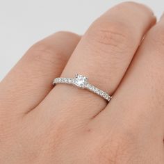 a woman's hand with a diamond ring on top of her finger and the band is