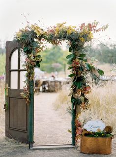 an open door with flowers and greenery on the outside is shown in this photo