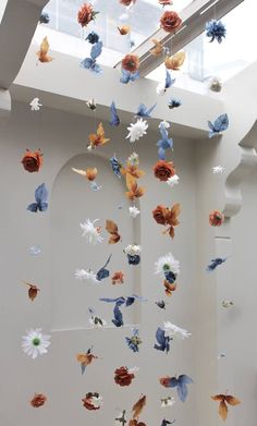 paper flowers are suspended from the ceiling in an art gallery