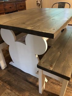 a wooden table and bench with mickey mouse ears on the top, sitting in a living room