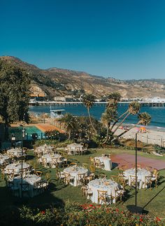 tables and chairs are set up on the lawn by the water