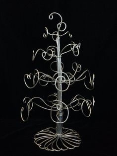 a metal christmas tree with hearts on it's sides and swirls around the base