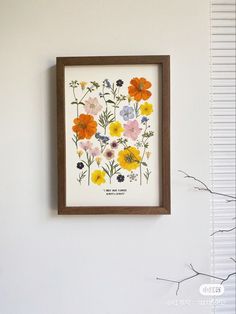 a framed flower print hanging on the wall