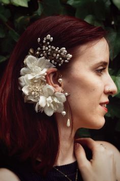 a woman with red hair wearing a white flower clip