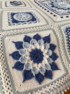 a blue and white crocheted blanket on top of a wooden floor