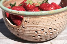 a bowl filled with strawberries sitting on top of a wooden table