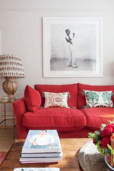 a living room with red couches and pictures on the wall above them, along with coffee table