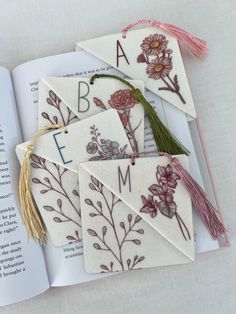 the book is open and has embroidered flowers on it, along with tassels