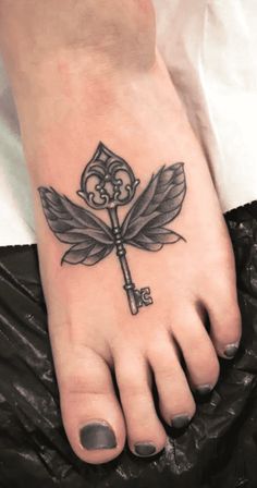 a person's foot with a tattoo on it and a key in the middle