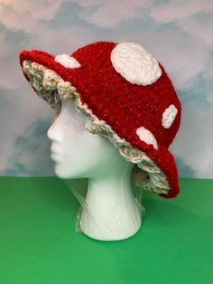 a red and white crocheted hat on top of a mannequin head