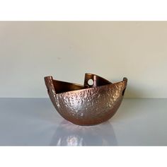 a large metal bowl sitting on top of a table next to a white wall and floor