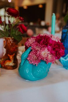 colorful flowers are in blue vases on a white tablecloth with candles and other decorations