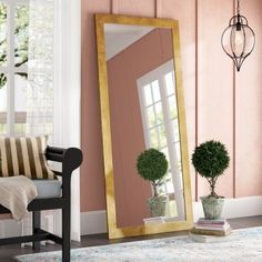 a mirror sitting on top of a wooden floor next to a chair and potted plant