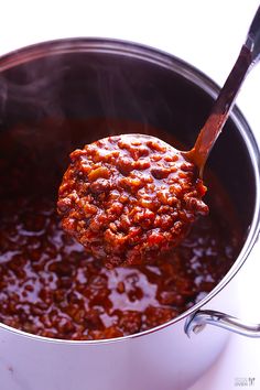 a ladle full of chili sauce with a wooden spoon