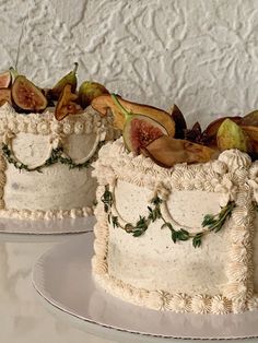 two cakes decorated with figurines and leaves on top of each other, sitting on plates