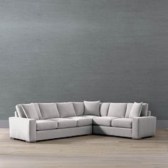 a large sectional couch with pillows on the back and sides, in front of a gray wall