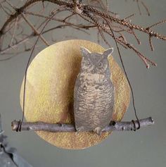 an owl figurine sitting on top of a branch next to a round object