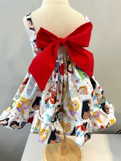 a dress on a mannequin with a red bow around the neck and cartoon characters all over it