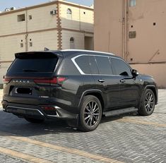 the rear end of a black suv parked in front of a building on a cobblestone street