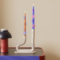 two candles are sitting on a table next to a vase