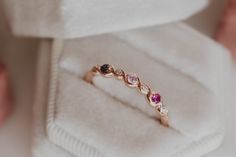 a ring with three different colored stones in it sitting on top of a white box