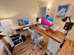 a computer desk with two monitors and speakers on top of it in a home office