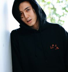 a young man wearing a black hoodie and looking off into the distance