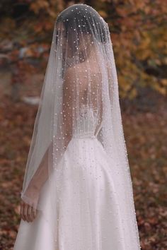 a woman wearing a wedding veil with pearls on it