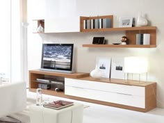 a living room with white furniture and shelves on the wall, including a flat screen tv