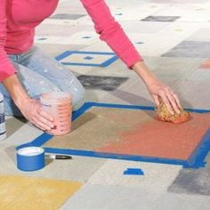 a woman kneeling down on the floor with a cup and paintbrush in her hand