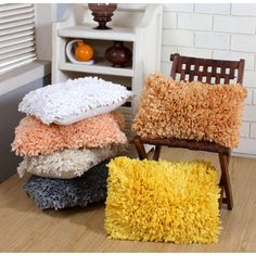 four pillows stacked on top of each other in front of a book shelf and chair