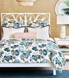 a white bed with blue and green floral bedspread on it in a bedroom