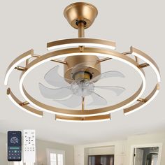 a ceiling fan with remote controls in a living room or dining room area that is white and gold