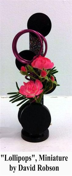 a black vase with pink flowers in it and the words lollipops, miniatureture by david robinson