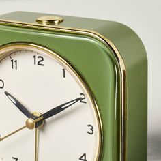 a green square clock with gold trim around the face and numbers on both sides, sitting in front of a white background